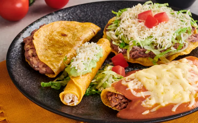 Quesadilla, flautas y enchilada servidas sobre mantel amarillo